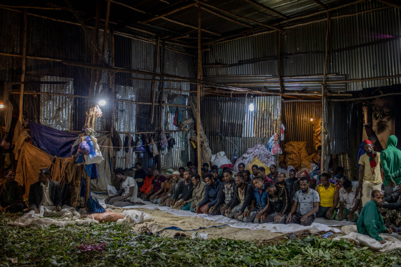 Daniel Etter: Chat (Catha edulis) sorters, porters and buyers pray in one of the biggest chat trading and sorting shops in Awaday, Ethiopia, Nov. 5, 2019. The chat sorted and traded here is intended for export to Somaliland. The shop is owned by a Somalilandian company Faraska A'ad (The White Horse). According to managers here,  the turnaround in this shop alone is 170,000 USD per day. Awaday is the hub of the Ethiopian chat trade. All internal and external trade of the drug from the surrounding growing region of Harar goes through here. The drug is widely consumed on the Horn of Africa and the Arabian Peninsula, especially Yemen. Depending on region it is known, amongst many other names, as khat, gat, qat, khat or jimaa.