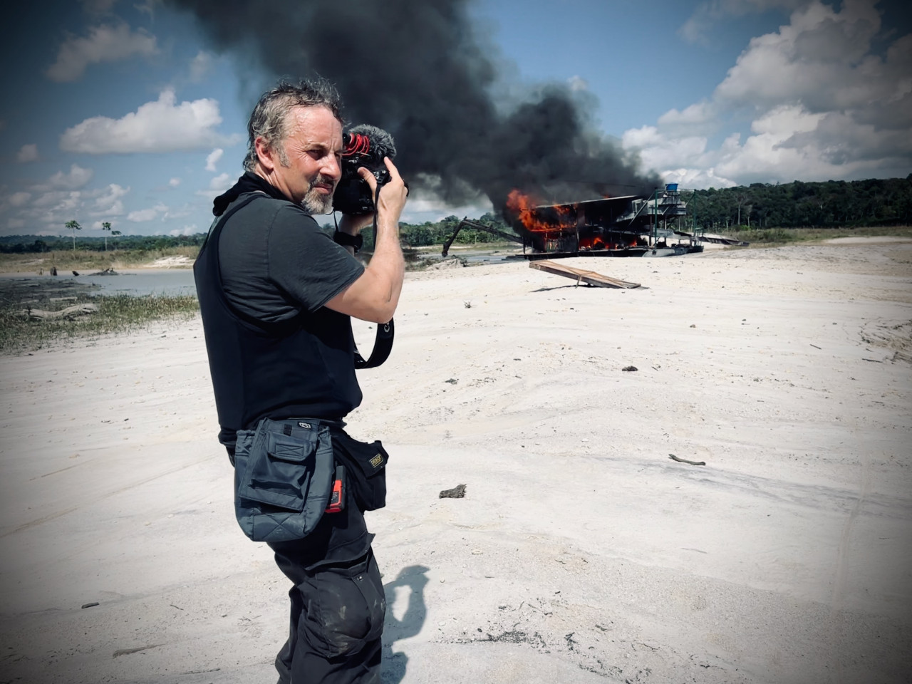 FPC491 - Im Gespräch mit Filmemacher und Regisseur Richard Ladkani, seine Arbeiten und die Zeit mit Jane Goodall 27 Fotopodcast YANUNI Richard Ladkani in front of burning Gold Dredger Copyright MalaikaPictures
